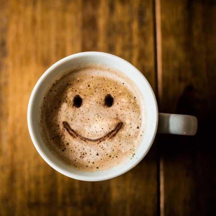 Overhead photograph of a coffee cup with a smiling face in the foam.